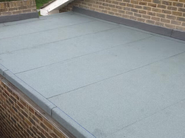Newly installed grey felt flat roof with sealed joins and raised edge detailing.